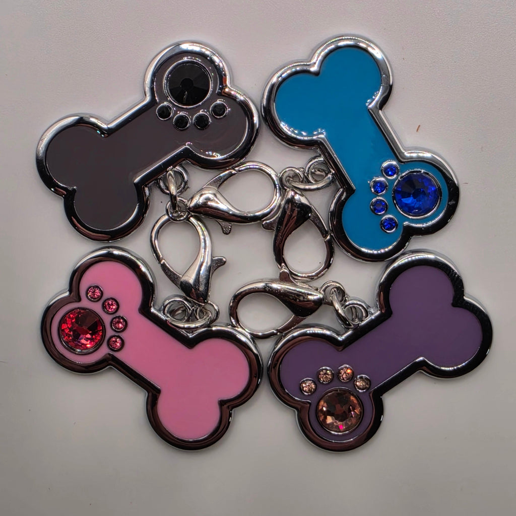 Set of colorful bone-shaped charms with rhinestones on a light gray background
