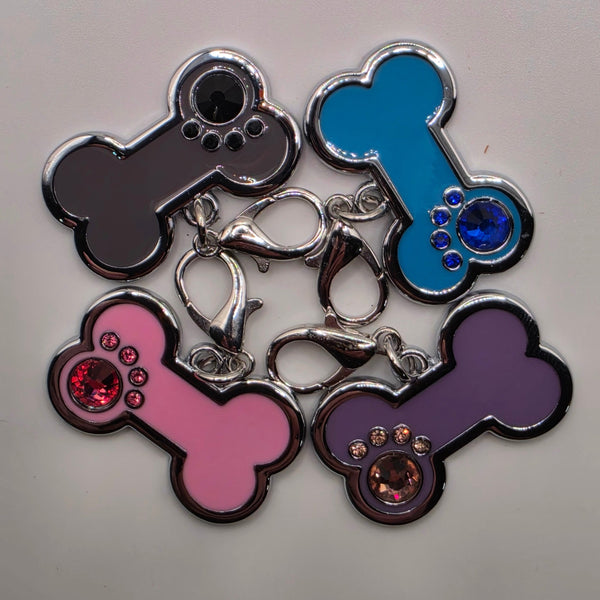 Set of colorful bone-shaped charms with rhinestones on a light gray background