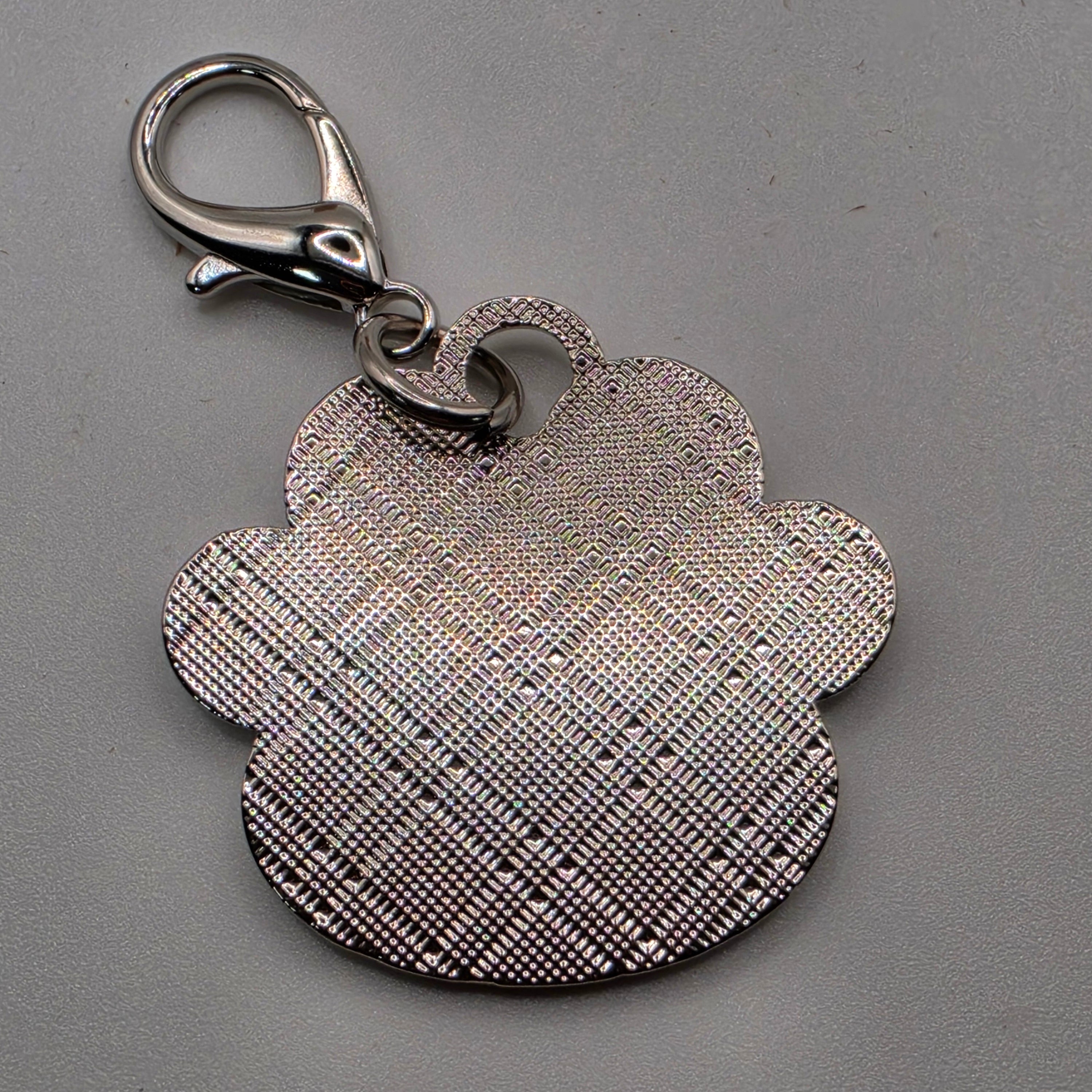 Metallic paw-shaped keychain with a clasp on a gray background