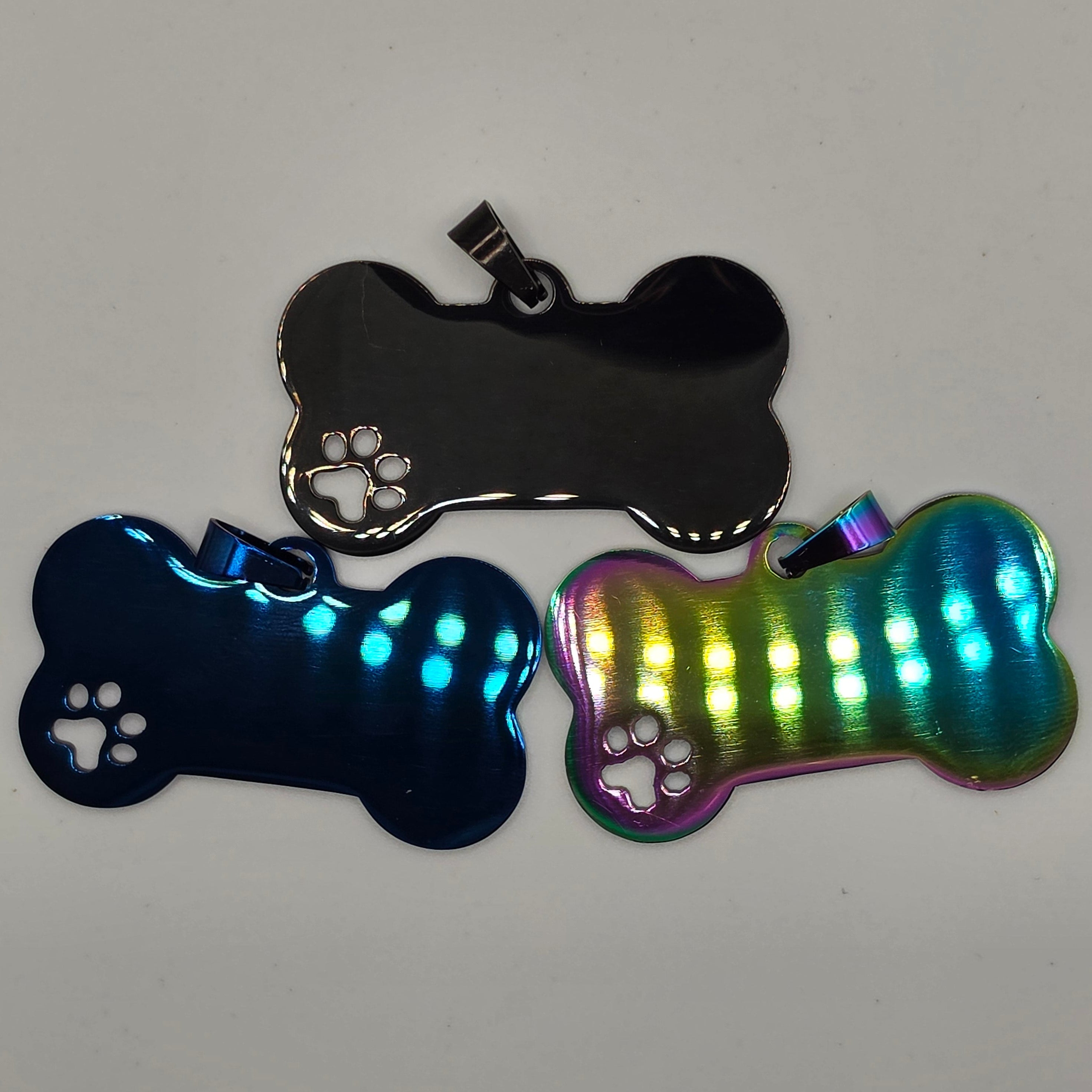 Three metallic dog bone-shaped keychains on a light gray background