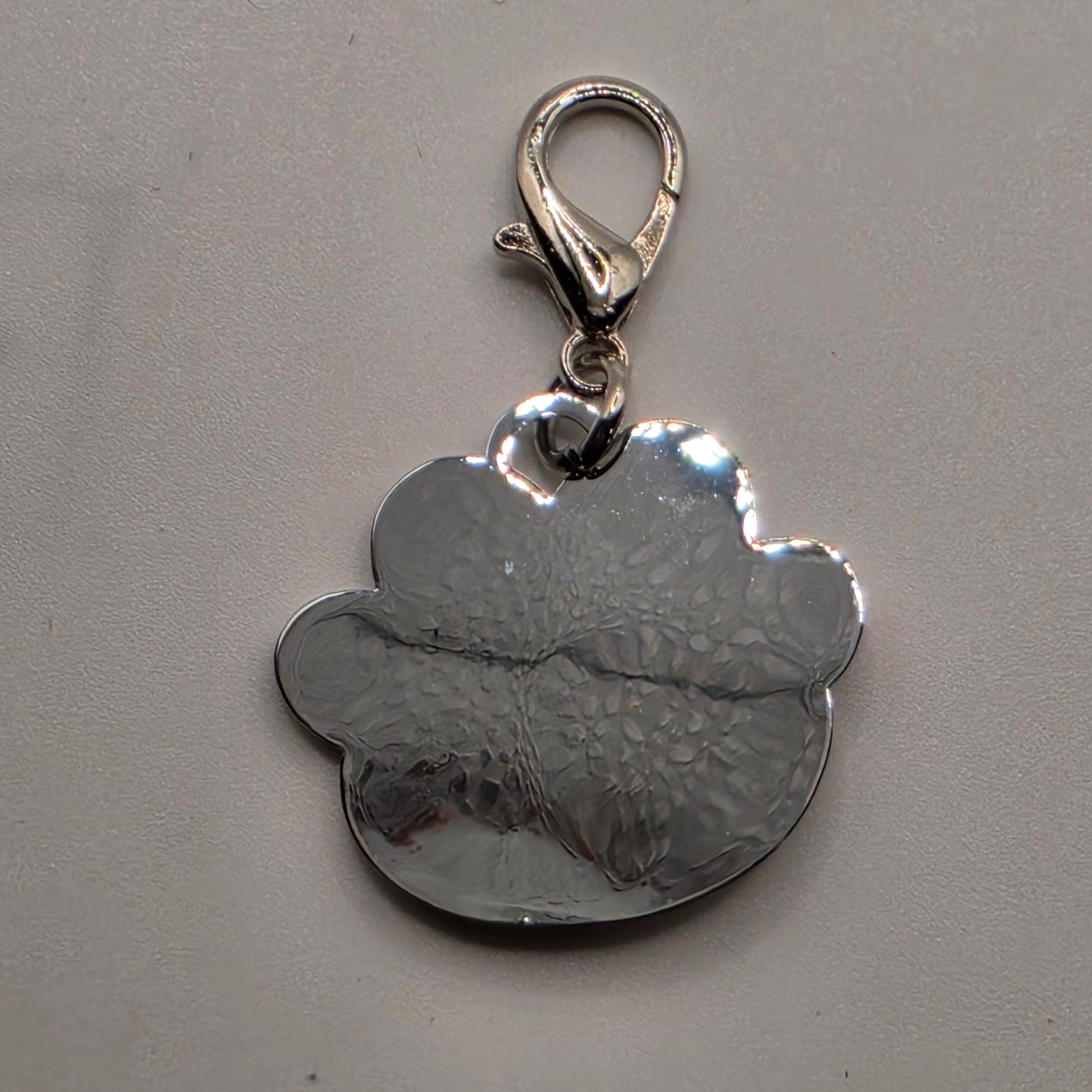 Silver dog tag with a textured design on a gray background