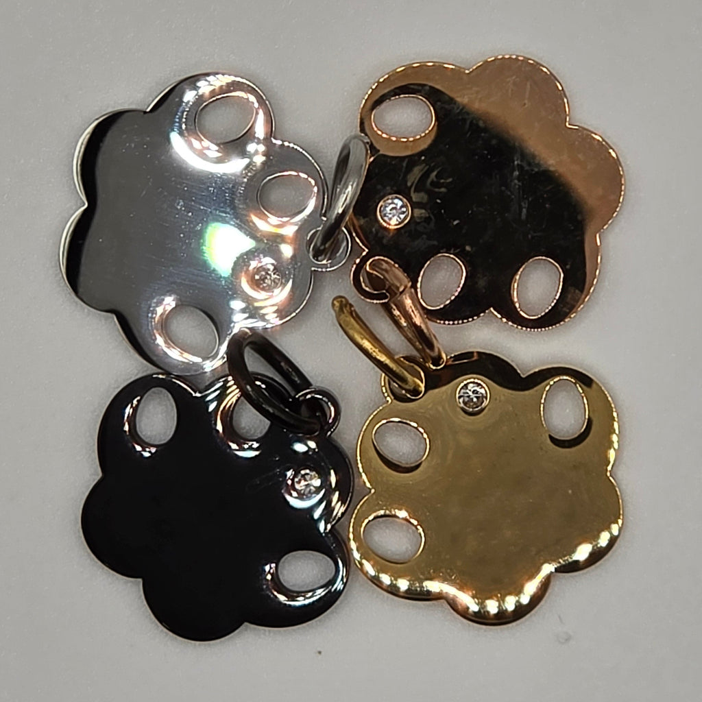 Four metallic charms in gold, silver, and black on a gray background