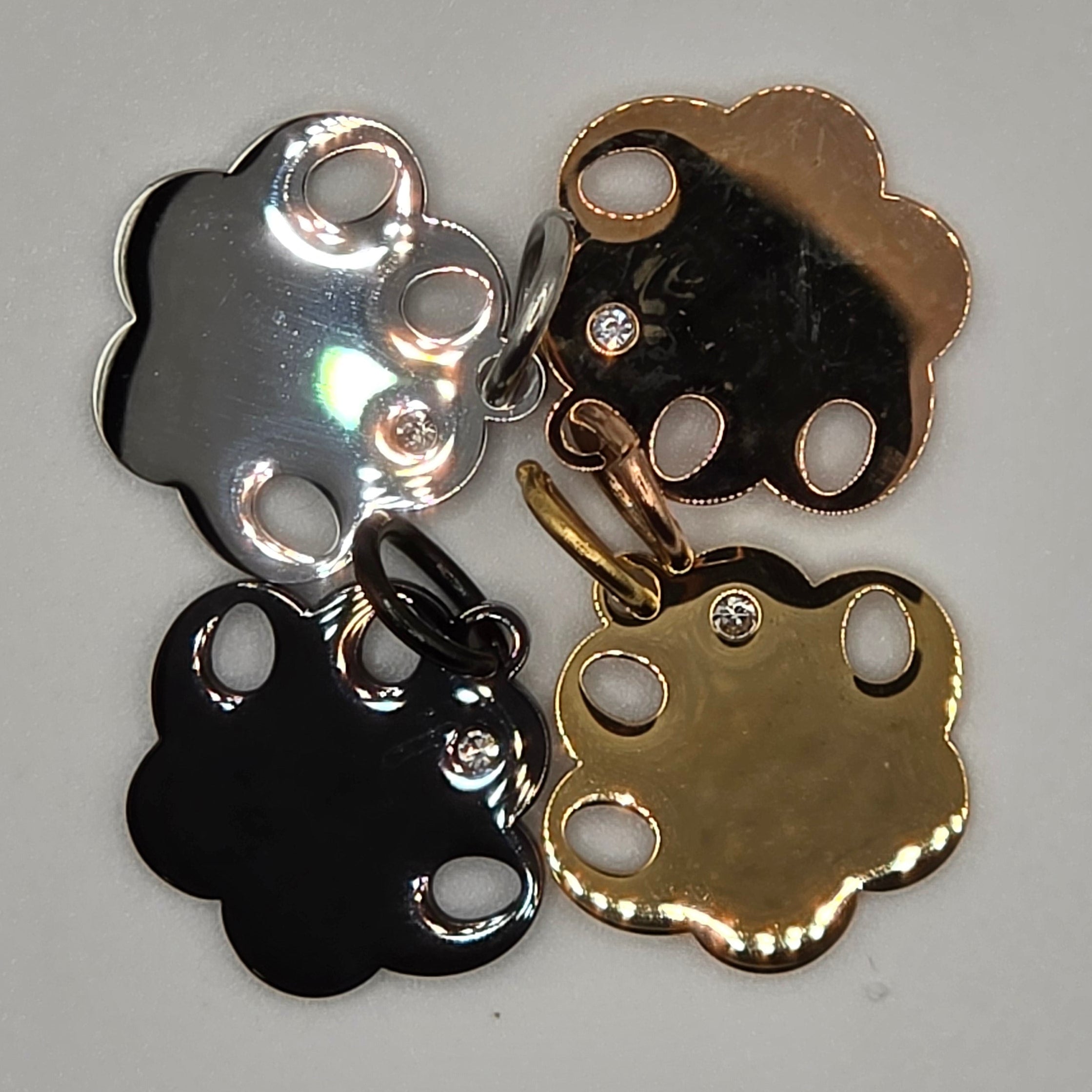 Four metallic charms in gold, silver, and black on a gray background