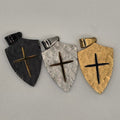 Three arrowhead-shaped hair clips in gold, silver, and black on a gray background