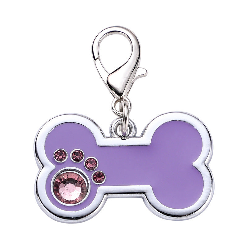 Purple bone-shaped pet tag with pink crystals on a white background