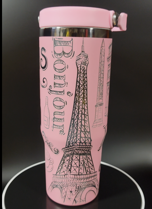 Pink tumbler with Eiffel Tower design and 'Bonjour' text on a dark background