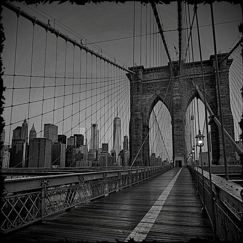 Black and white view of the Brooklyn Bridge towards the Manhattan skyline