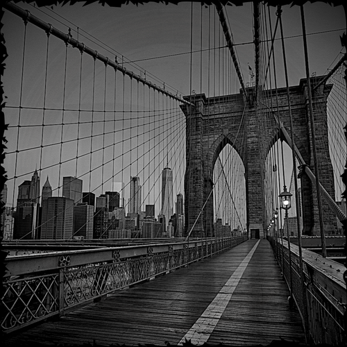 Black and white view of the Brooklyn Bridge towards the Manhattan skyline