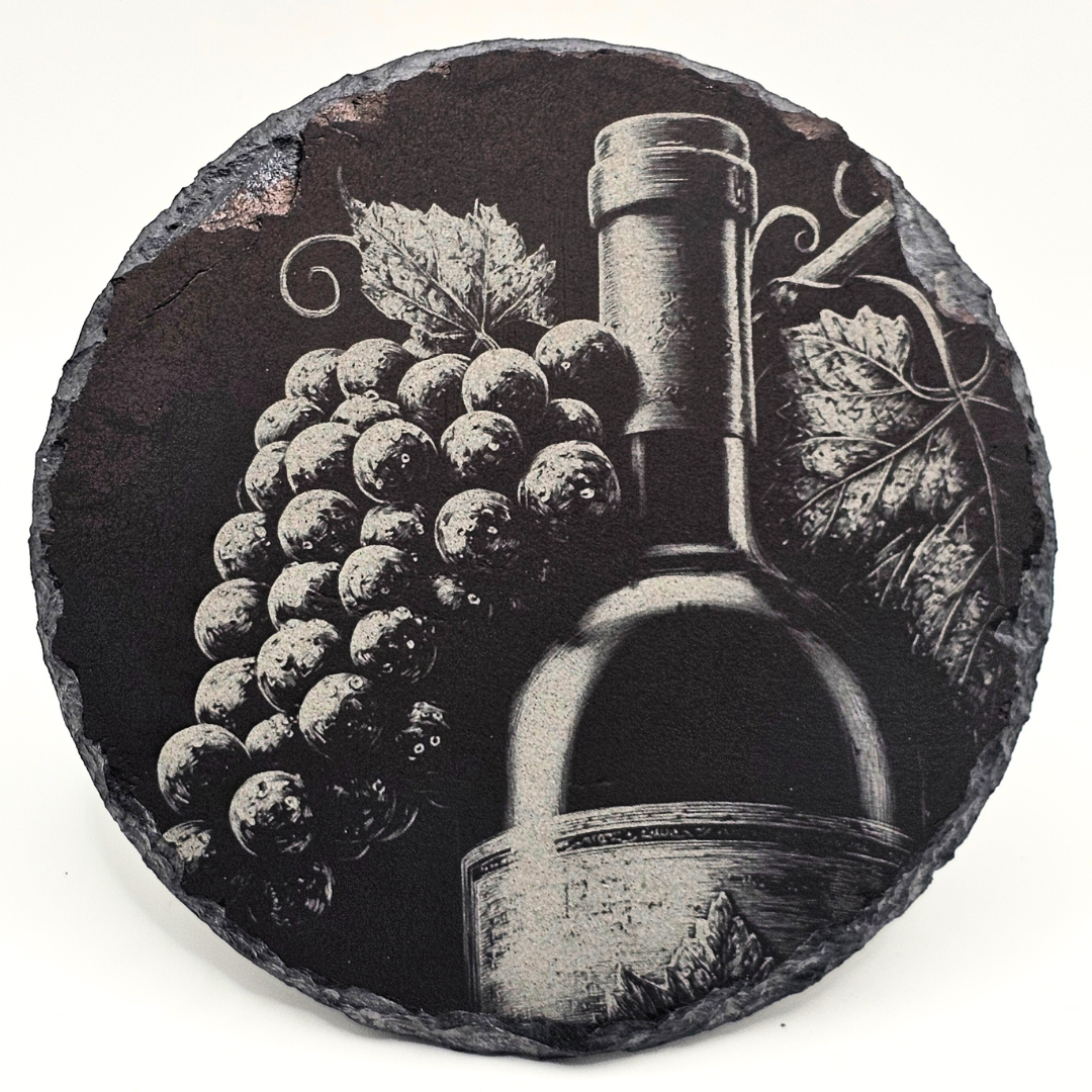 Decorative stone with engraved design of a wine bottle and grapes on a white background
