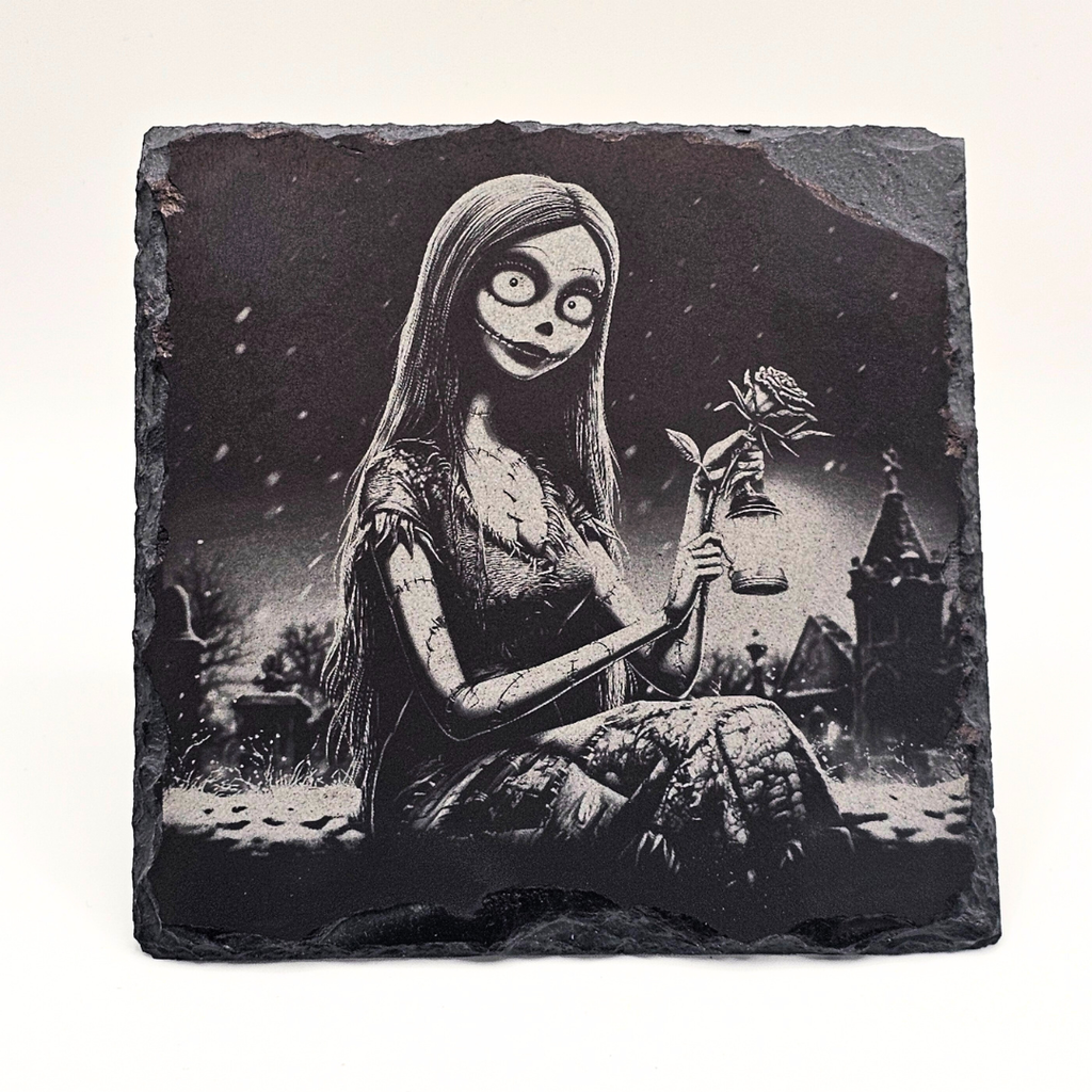 Decorative stone with a black and white illustration of a character holding a flower in a dark, gothic setting.