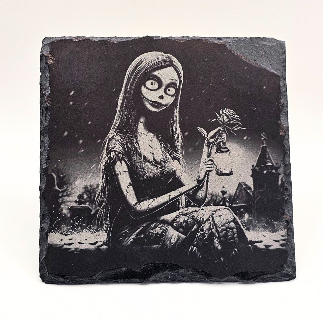 Decorative stone with a black and white illustration of a character holding a flower in a dark, gothic setting.