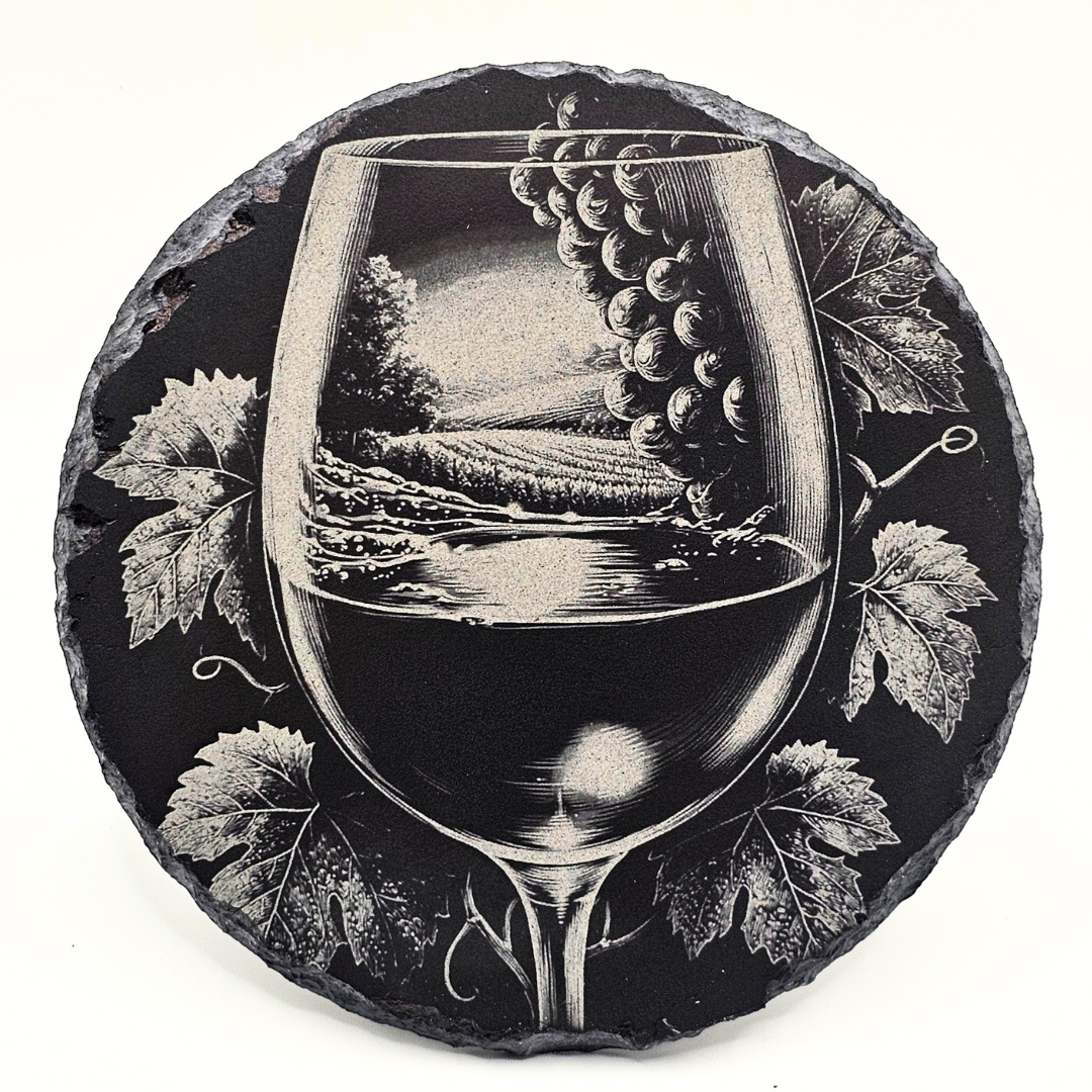 Decorative stone coaster with a wine glass and grapes design on a black background