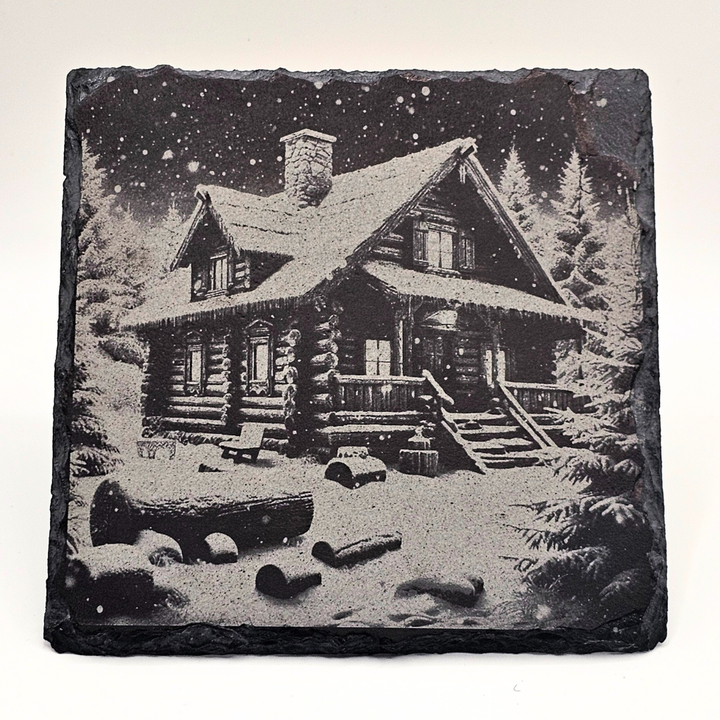 Decorative stone with a engraved image of a log cabin in the woods.