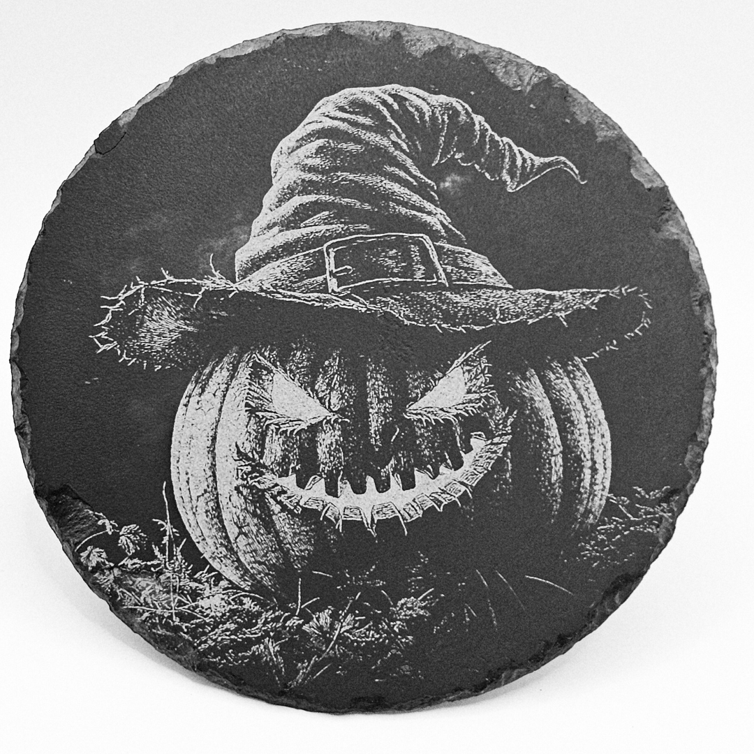 Decorative stone with a carved pumpkin and witch hat design on a white background
