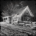 Wooden cabin decorated with string lights at night in a snowy landscape