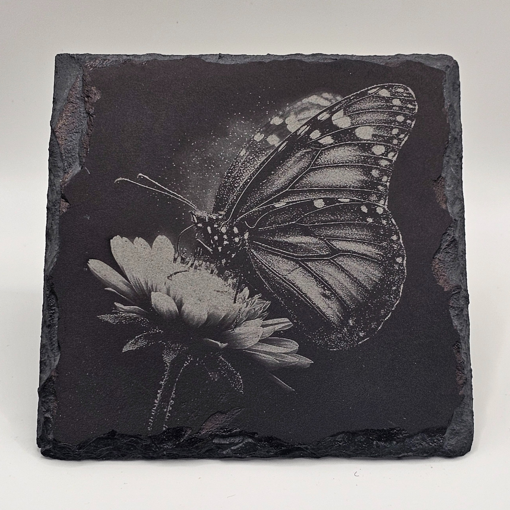 Black slate tile with engraved butterfly and flower design on a white background