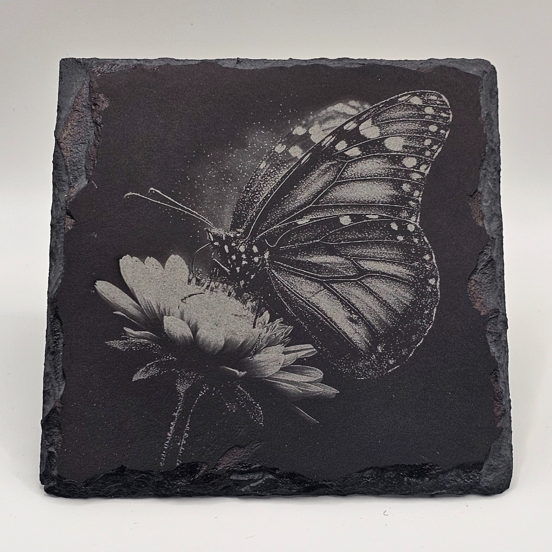 Black slate tile with engraved butterfly and flower design on a white background