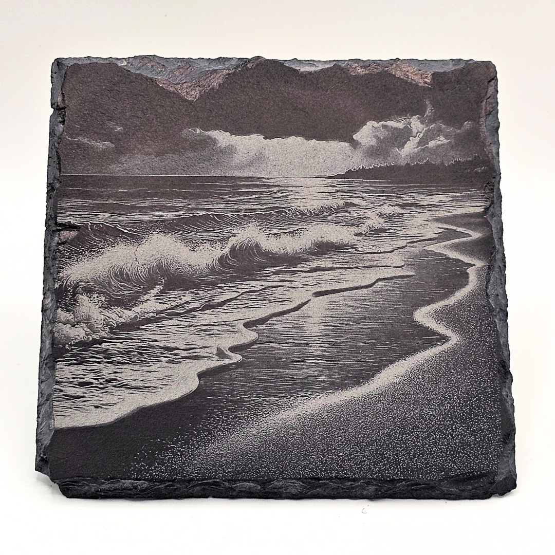 Slate with engraved image of a beach scene with waves and clouds.