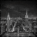 Black and white night view of a city skyline with prominent buildings.