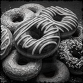Stack of various donuts with different toppings in black and white.