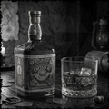 Captain Malt bottle with a glass of whiskey on a wooden surface with coins.