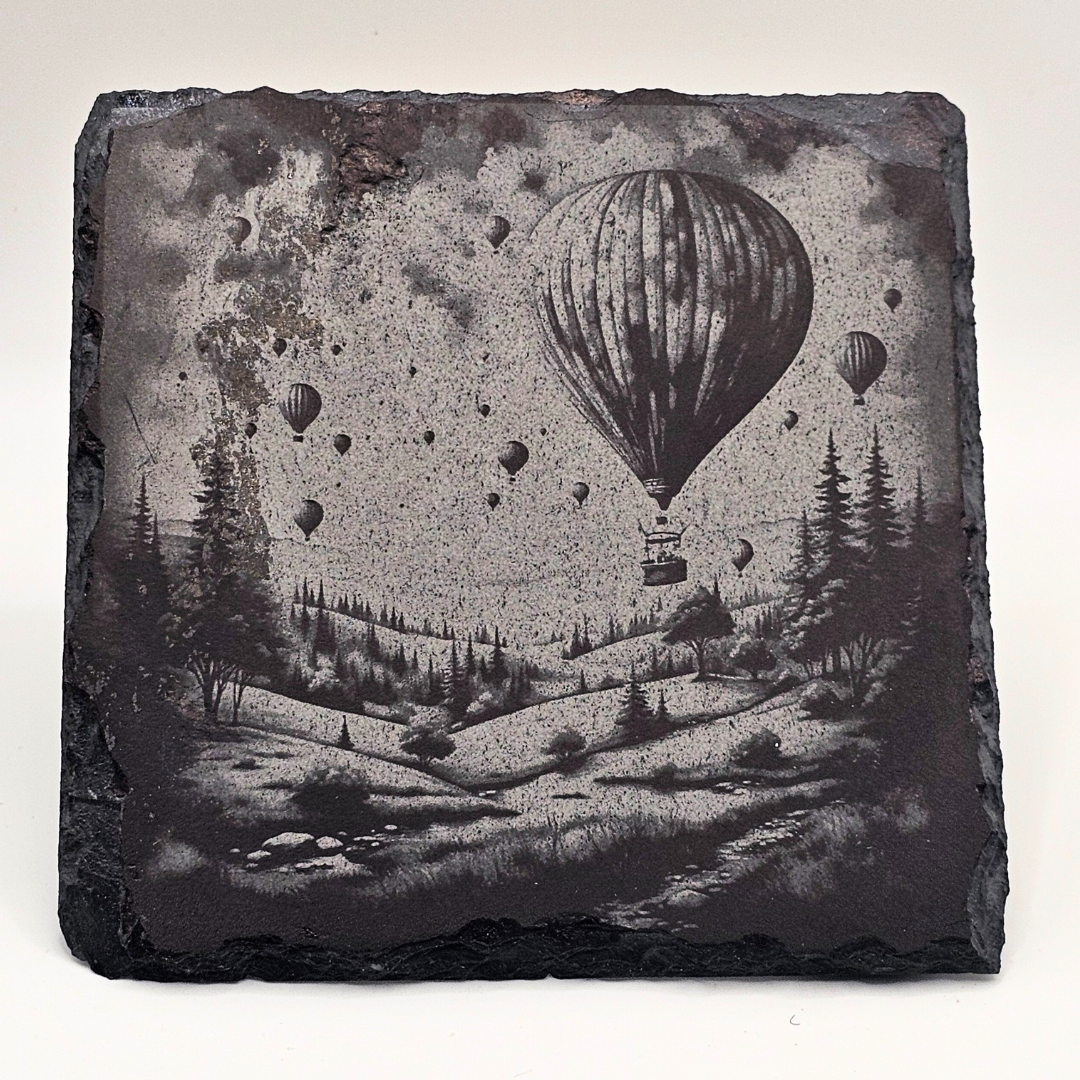 Decorative stone with engraved scene of hot air balloons over a landscape