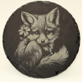 Round slate coaster with a black and white illustration of a fox holding a flower.