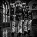 Four military personnel in formal uniforms with rifles marching indoors.