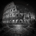 Black and white image of the Colosseum at night with stars in the sky.