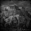 Black and white image of an ancient temple on a rocky outcrop with a dramatic sky.