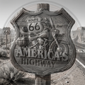 Decorative sign featuring Route 66 with a motorcycle illustration, set against a desert landscape.