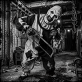 Horror clown with chainsaw in a dark, industrial setting
