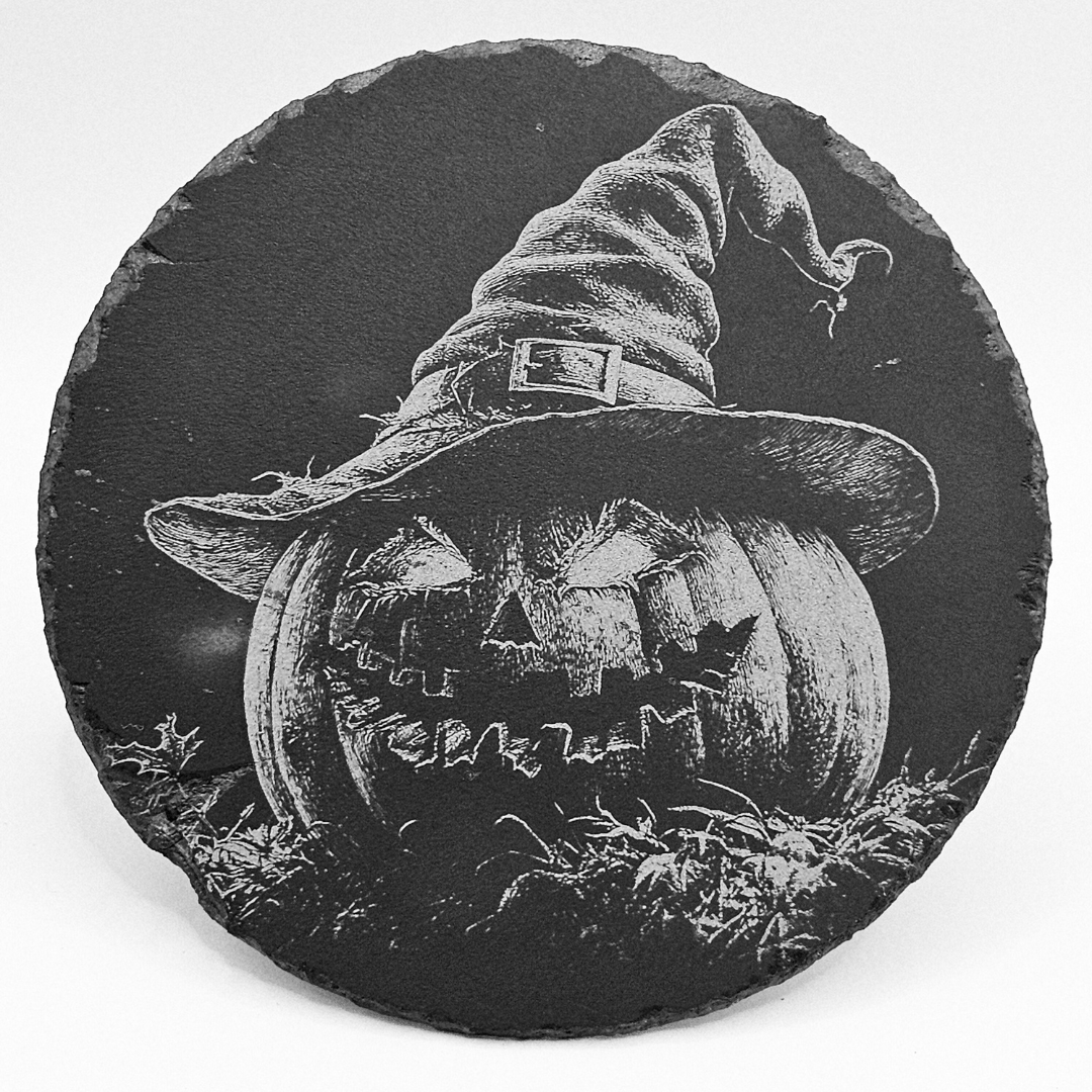 Round slate coaster with a Halloween design of a pumpkin wearing a witch hat.