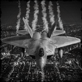 Fighter jet flying over a cityscape with smoke trails