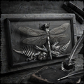 Wooden relief sculpture of a dragonfly on a wooden surface with books and an inkwell.