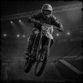 Motocross rider in mid-air over a jump with a dark, gritty background