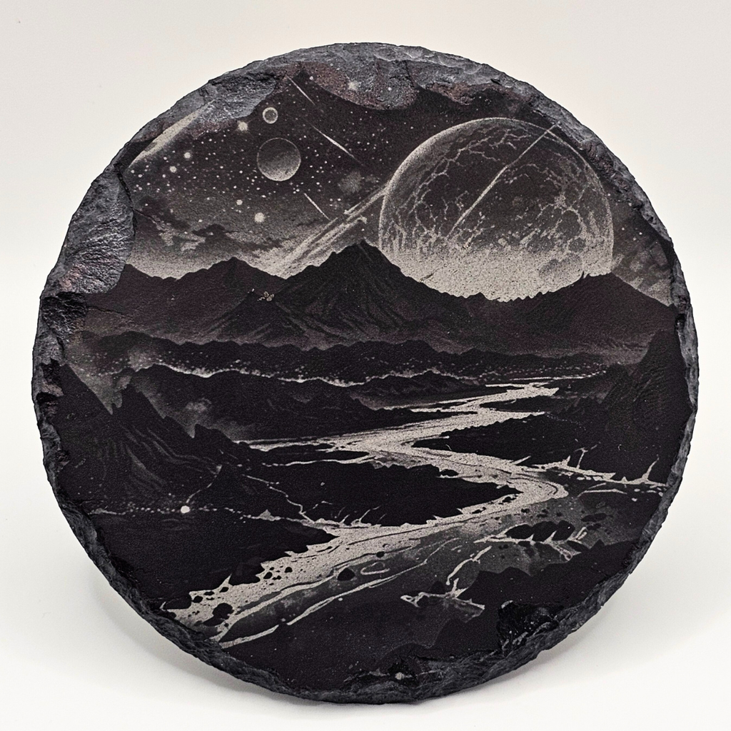 Decorative stone with engraved landscape of mountains and celestial bodies on a white background