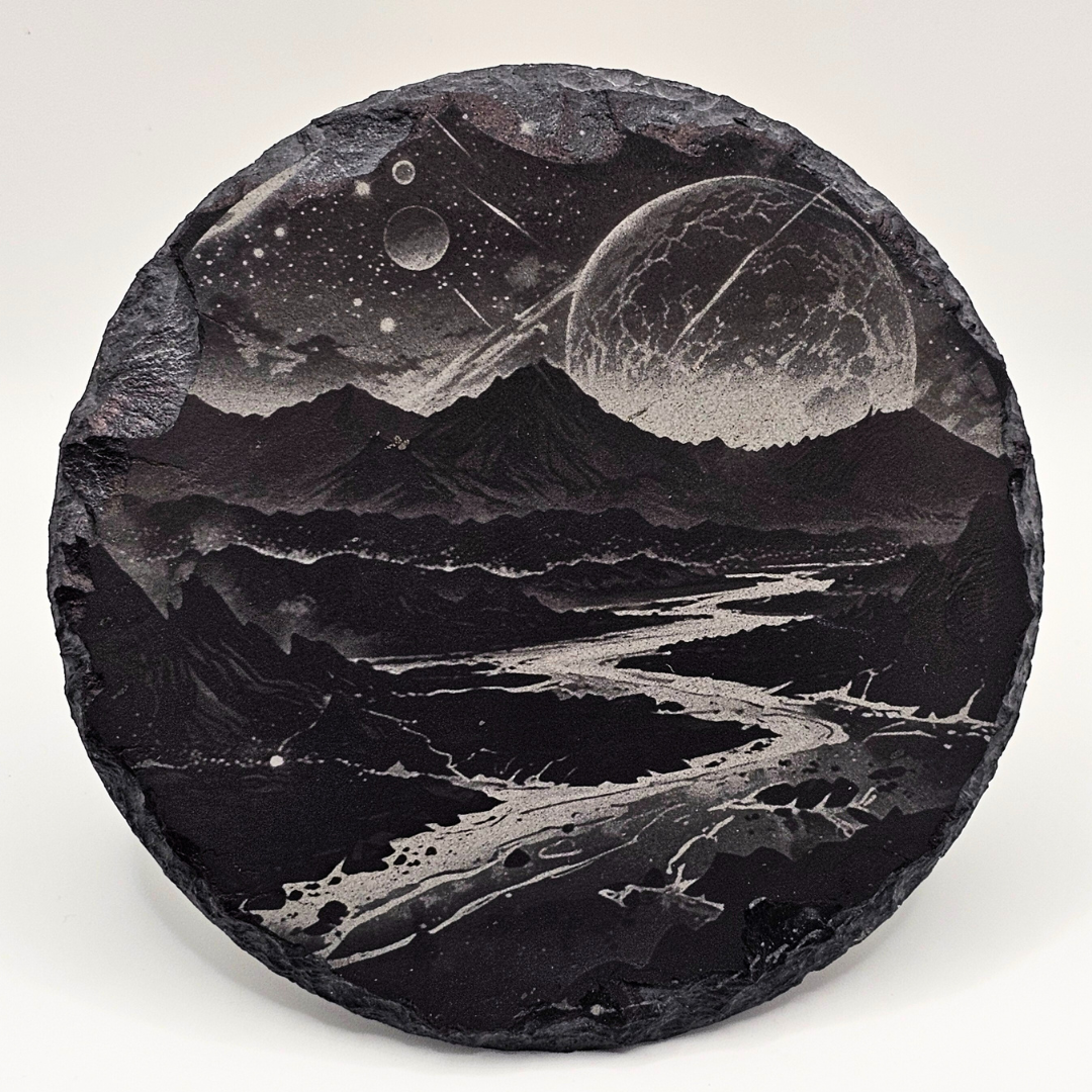 Decorative stone with engraved landscape of mountains and celestial bodies on a white background