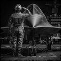 Person in military uniform saluting a fighter jet in a hangar