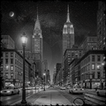 City street at night with tall buildings and streetlights, featuring iconic skyscrapers.